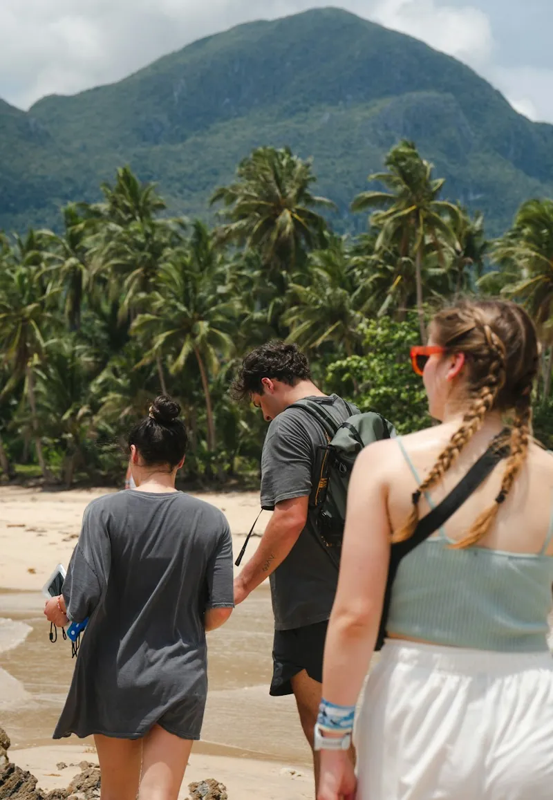 Grupo de turistas caminhando pela areia entre coqueiros
